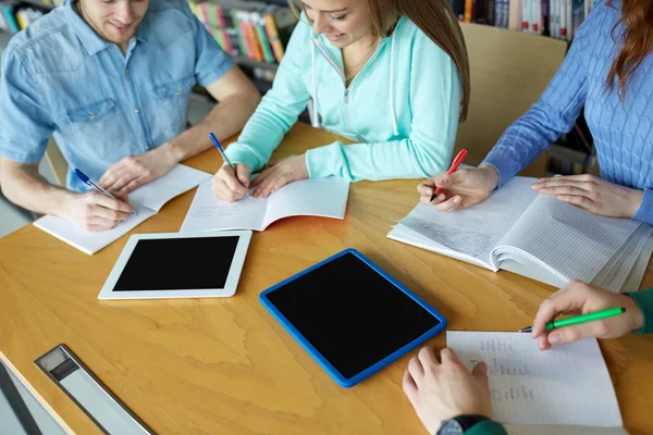 Zadowoleni uczniowie pisanie do notebooków w bibliotece — Zdjęcie stockowe