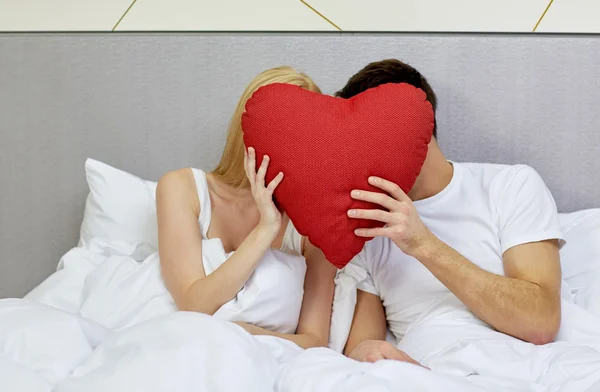 Szczęśliwa para w łóżku z czerwonym sercem kształt poduszki — Zdjęcie stockowe