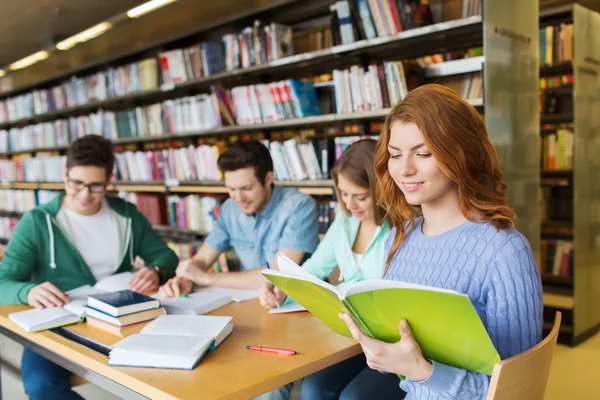 Happy students reading books in library — Stock Photo, Image