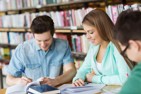 Studenten met boeken die zich voorbereiden op een examen in de bibliotheek — Stockfoto