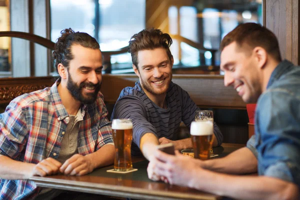 Manliga vänner med smartphone dricka öl på bar — Stockfoto