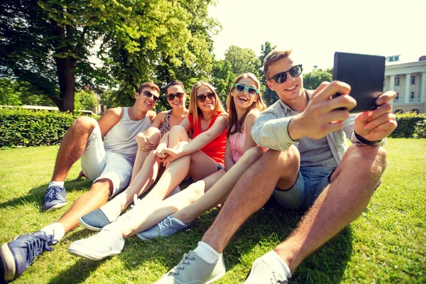 Smiling friends with tablet pc computer in park — Stock Photo, Image