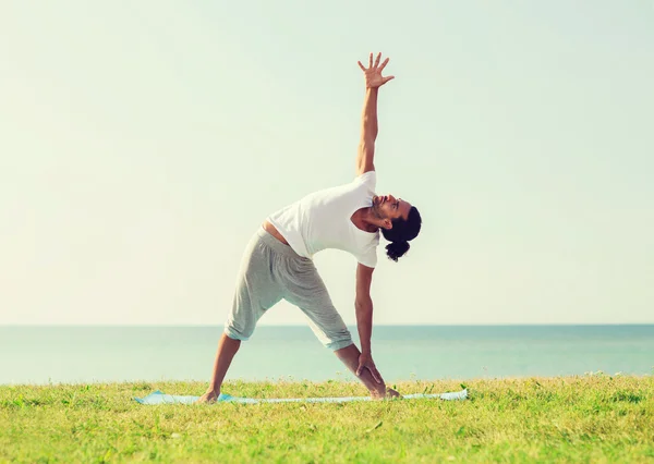 Homem sorrindo fazendo exercícios de ioga ao ar livre — Fotografia de Stock