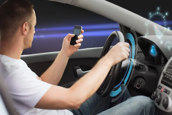 Man looking to smarphone while driving car — стоковое фото