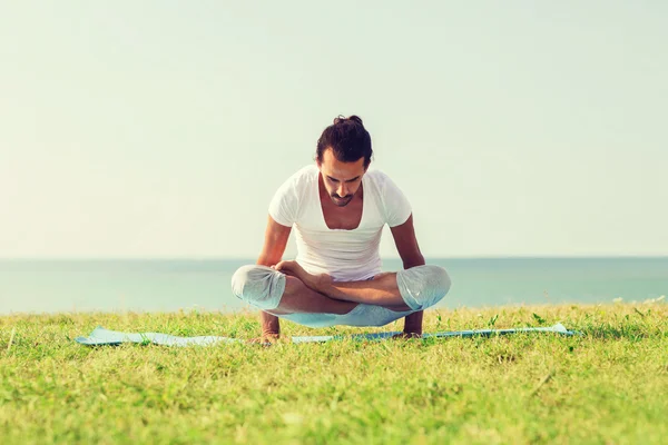 Leende mannen att göra yoga övningar utomhus — Stockfoto