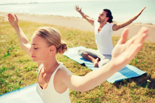 Pareja sonriente haciendo ejercicios de yoga al aire libre — Foto de Stock