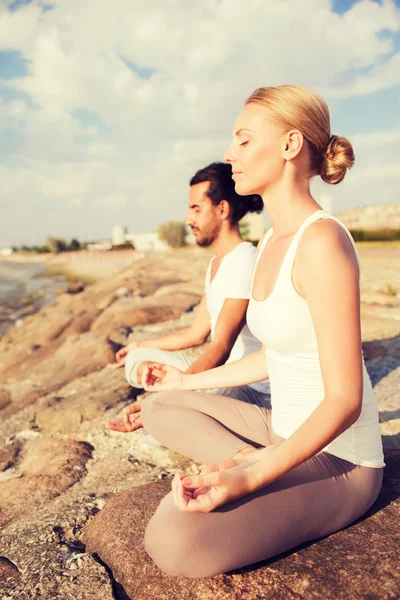 Lächelndes Paar macht Yoga-Übungen im Freien — Stockfoto