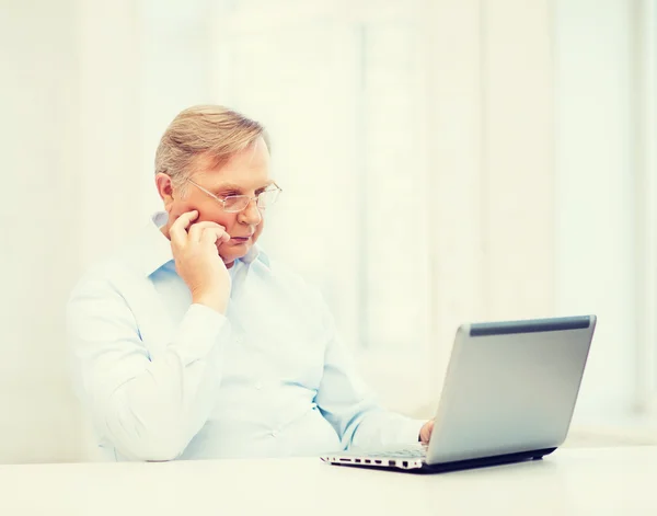 Oude man in brillen werken met laptop thuis — Stockfoto