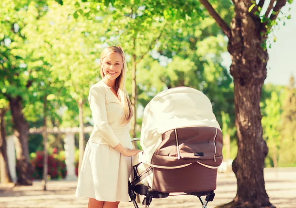 Gelukkig moeder met wandelwagen in park — Stockfoto