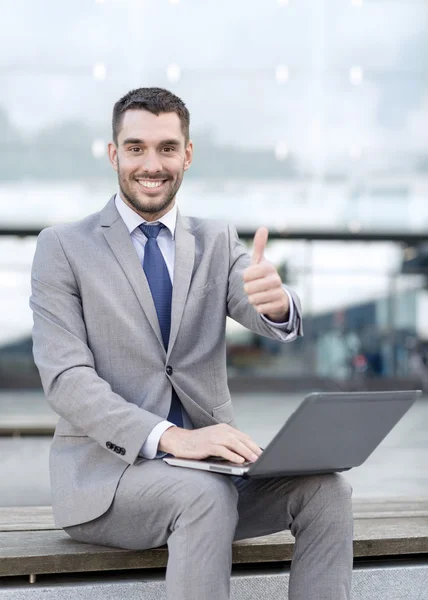 Homem de negócios sorrindo trabalhando com laptop ao ar livre — Fotografia de Stock