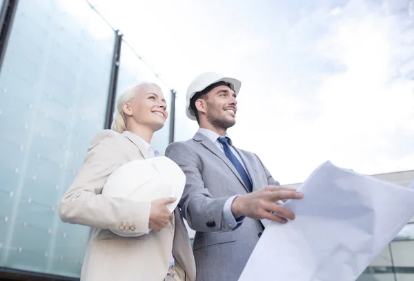 Lächelnde Geschäftsleute mit Blaupause und Helm — Stockfoto