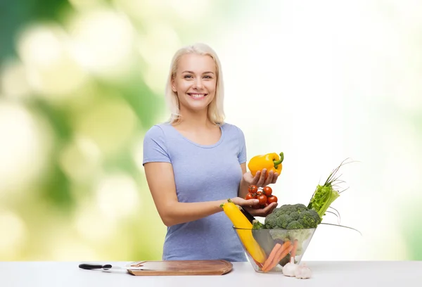 Smiling young woman cooking vegetables over green — Stock Photo, Image