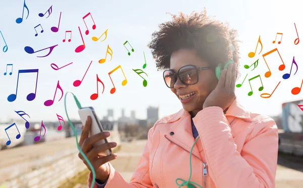 Gelukkig jonge vrouw met smartphone en hoofdtelefoons — Stockfoto