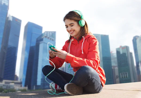 Feliz joven con teléfono inteligente y auriculares —  Fotos de Stock