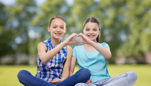 Happy little girls showing heart shape hand sign — Stock Photo, Image