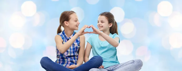 Šťastný holčičky ukazující tvar srdce rukou znamení — Stock fotografie