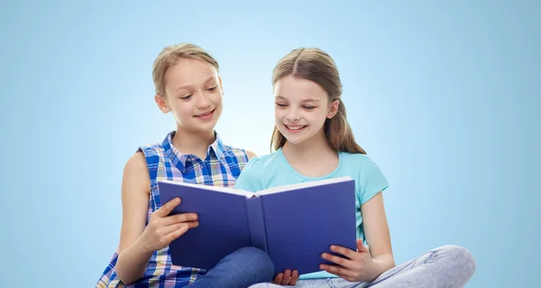 Duas meninas felizes ler livro sobre fundo azul — Fotografia de Stock