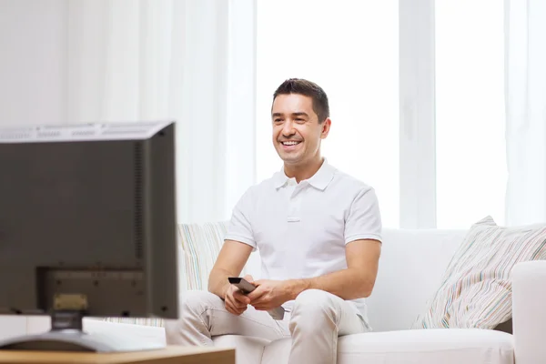 Sorrindo homem com controle remoto assistindo tv — Fotografia de Stock