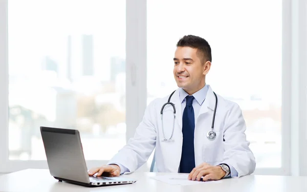 Sorridente médico masculino com laptop em consultório médico — Fotografia de Stock