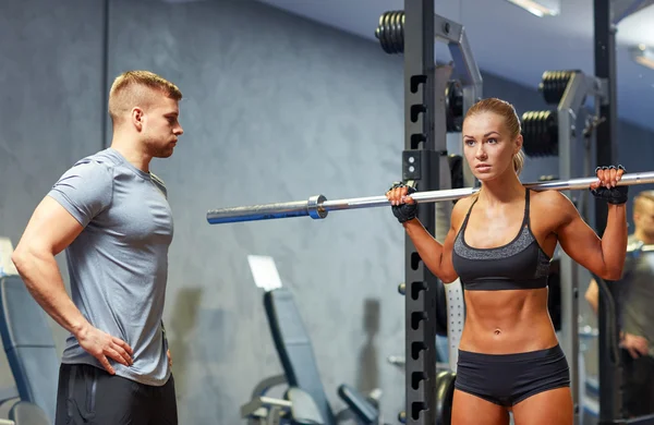 Man en vrouw met lange halter flexing spieren in de sportschool — Stockfoto