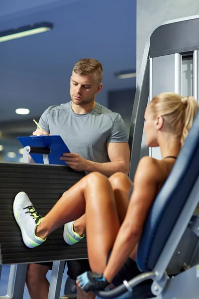 Hombres y mujeres flexionando los músculos en la máquina de gimnasio —  Fotos de Stock