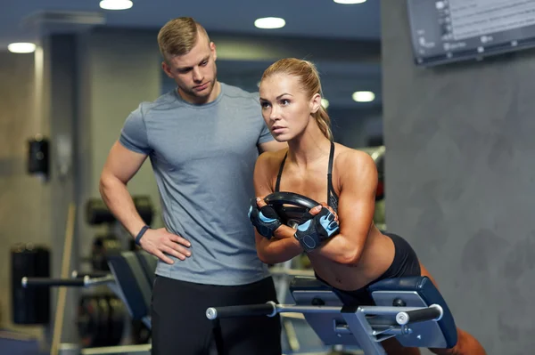 Femme avec entraîneur personnel flexion des muscles dans la salle de gym — Photo