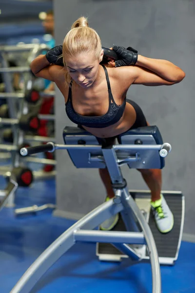 Молодая женщина сгибает мышцы на скамейке в спортзале — стоковое фото