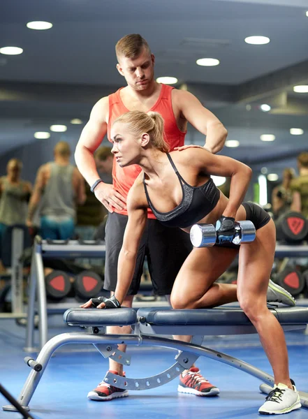 Giovane coppia con manubri che flettono i muscoli in palestra — Foto Stock