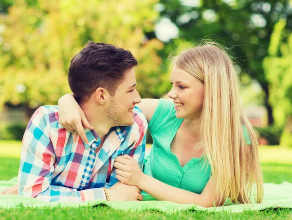 Sorrindo casal deitado em cobertor no parque — Fotografia de Stock