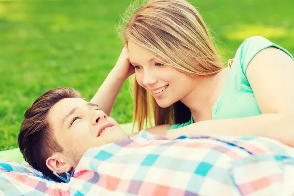 Coppia sorridente sdraiata su una coperta nel parco — Foto Stock