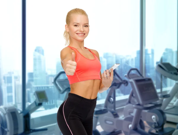 Mujer deportiva sonriente con teléfono inteligente en el gimnasio —  Fotos de Stock