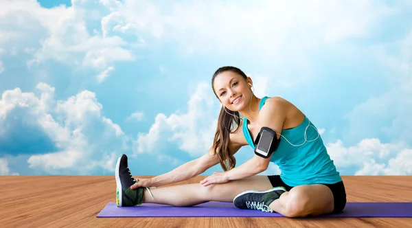 Smiling woman stretching leg on mat over clouds — Stock Photo, Image