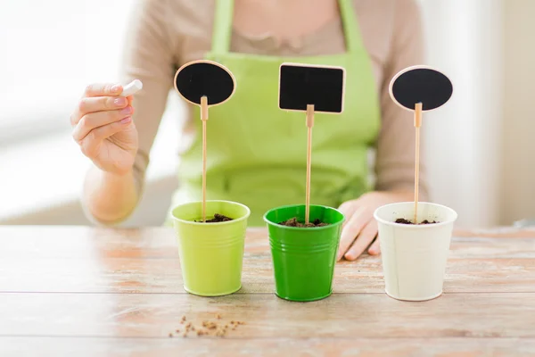 Close up of woman over pots with soil and signs — Stock Photo, Image