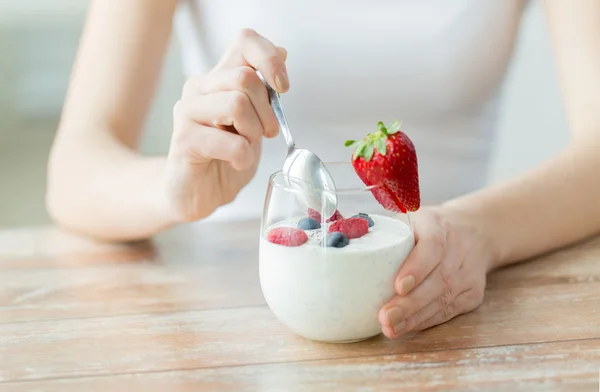 Perto de mãos de mulher com iogurte e bagas — Fotografia de Stock