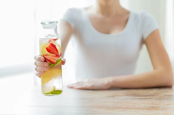 Close up of woman with fruit water in glass bottle — Stock Photo, Image