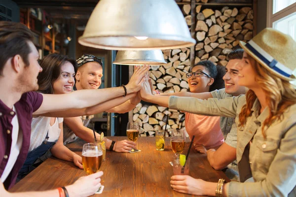 Amis heureux avec des boissons faisant cinq haut au bar — Photo