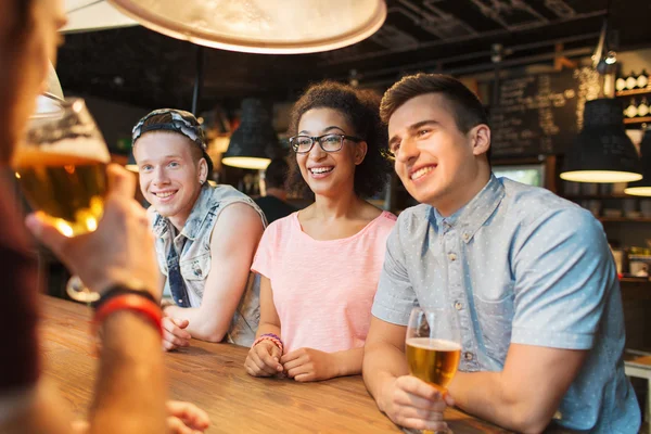 Amigos felizes bebendo cerveja e conversando no bar — Fotografia de Stock