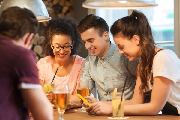 Amigos felices con teléfonos inteligentes y bebidas en el bar — Foto de Stock