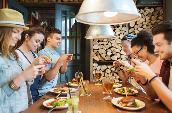 Amigos felizes com smartphones imaginando comida — Fotografia de Stock