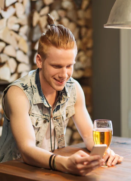 Homem feliz com smartphone bebendo cerveja no bar — Fotografia de Stock