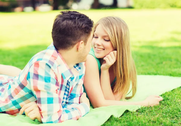 Smiling couple lying on blanket in park — Stock Photo, Image