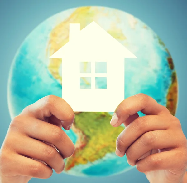 Couple hands holding green house over earth globe — Stock Photo, Image