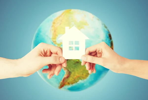 Couple hands holding green house over earth globe — Stock Photo, Image