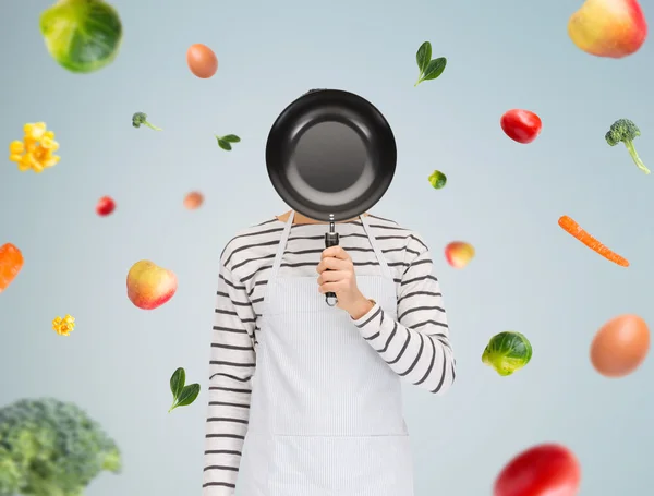 Mann oder Köchin in Schürze versteckt Gesicht hinter Pfanne — Stockfoto