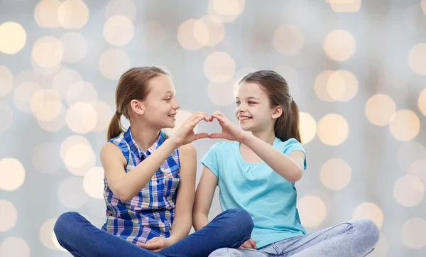 Щасливі маленькі дівчата, що показують знак руки у формі серця — стокове фото