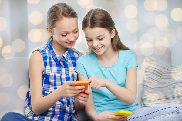 Meninas felizes com smartphones sentados no sofá — Fotografia de Stock