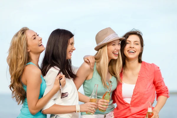 Filles souriantes avec des boissons sur la plage — Photo