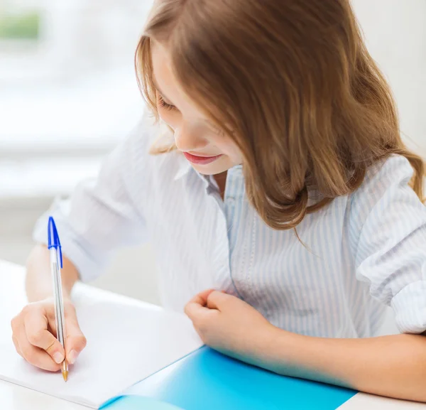 女学生在学校里的笔记本中写 — 图库照片