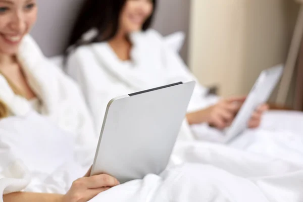 Mujeres felices en albornoces con tablet pc en el hotel —  Fotos de Stock