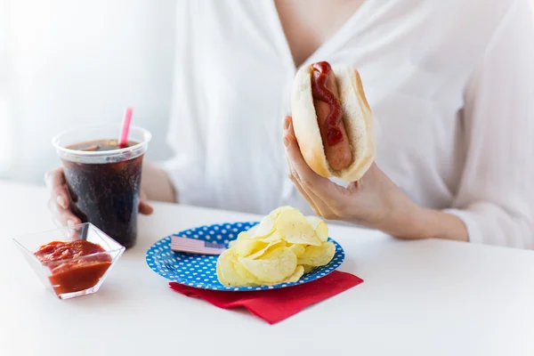 Närbild på kvinna äta varmkorv med coca cola — Stockfoto